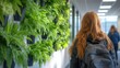 © wannathon - Woman Walking Past Green Foliage in Modern Indoor Setting
