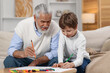 © New Africa - Grandpa and his grandson drawing at table indoors