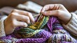 © INFORMAN - Close-Up of Hands Knitting a Colorful Scarf in a Cozy Indoor Setting
