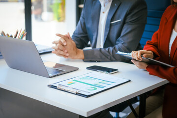 Wall Mural - A businessman and woman sit at a modern office table, smiling and discussing a new project or business startup. They collaborate with a laptop, focusing on strategic planning and teamwork