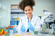 © NanSan - An African American female scientist works at her desk in a laboratory, closely examining a meat sample under a microscope.She focuses on modification,plant genetics,innovations in food meat research