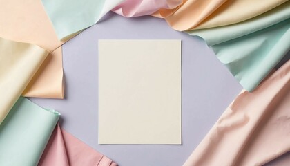 Wall Mural - Flat lay composition of blank paper surrounded by pastel fabrics