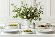 © colnihko - Elegant table setting with white floral centerpiece and fresh green olives