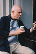 © BullRun - Pensive aged man with coffee and smartphone in cafe