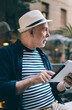 © BullRun - Serious aged man using tablet near modern cafe