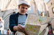 © BullRun - Cheerful senior man with map on street