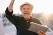 © BullRun - Positive matured man with tablet standing on street