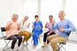 © artitwpd - The caregiver therapist sits with a group of Asian senior people with thumbs up in a circle for checking physical and mental health in a group elderly therapy session. The nursing home facilitates