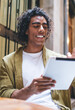 © BullRun - Joyful young African American student surfing tablet and smiling in cafeteria