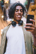 © BullRun - Positive black man with headphones using phone outside