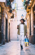 © BullRun - Focused young ethnic traveler with luggage bag walking on paved street