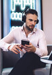 © BullRun - Caucasian businessman in earphones watching video webinar using bluetooth on touch pad and smartphone technology, successful professional in headphones connecting to 4g wireless internet on devices