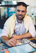 © BullRun - Portrait of cheerful male investor smiling at camera during money making in coworking space, successful businessman with modern touch pad and laptop technology posing at table with dollars