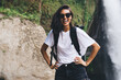 © BullRun - Happy female tourist with backpack standing near waterfall