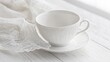 © siyons - Elegant White Teacup Rests on Saucer Beside Lace