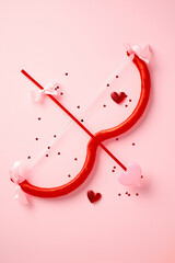 Wall Mural - Cupid bow and arrow with a heart on a pink background. Happy Valentine's Day, love, romance concept