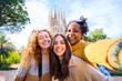 © CarlosBarquero - Young funny only women friends taking selfie in front of Sagrada Familia in Barcelona. Beautiful mixed race girl on street of European city enjoying vacation happy and smiling. Funny tourism people