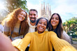 © CarlosBarquero - Group diverse funny young tourist friends posing piggyback with hands joined in air taking selfie together in front of Sagrada Familia in Barcelona. Adult happy excited people enjoy holidays outdoor