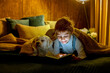 © Tomsickova - Little toddler child, boy, lying in bed with pet dog, little maltese dog, reading a book, soft light