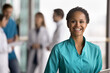 © fizkes - Head shot portrait African female therapist wear uniform standing in clinic hallway with tablet, laugh, look at camera. Professional medical services, nurse or healthcare administrator worker portrait
