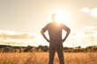 © kieferpix - Thoughtful man standing in a field facing the sun