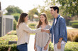 © fizkes - Happy young couple and real estate insurance agent shaking hands outdoors, meeting in suburb area for viewing house, giving greeting handshake, smiling, talking, standing outdoors