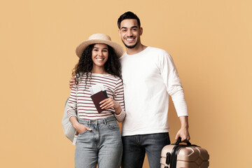 Wall Mural - Happy Middle Eastern Spouses With Travel Tickets And Luggage Posing Over Yellow Background, Cheerful Arabic Couple Carrying Passports And Suitcase And Smiling At Camera, Ready For Vacation Trip