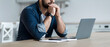 © Prostock-studio - Upset, sad, depression, frustrated and work at home. Concentrated pensive millennial bearded male looks at laptop and pressed hands to mouth, sits at table in kitchen interior, profile, panorama