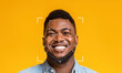 © Prostock-studio - A young man with a cheerful smile is captured against a vibrant yellow background. Facial recognition markers overlay his face, highlighting the technology's application in identification.
