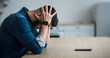© Prostock-studio - Dramatic at home, mental health problems, crisis, stress and expression negative emotions. Sad millennial man holding his head with hands, sitting at table with smartphone in living room interior