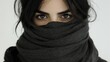© JO BLA CO - A young woman stands with her gaze focused, her eyes peering from behind a thick dark scarf. The background is simple, enhancing her enigmatic presence and expression