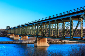 Wall Mural - A bridge spans a river, with a blue sky in the background