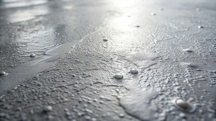 Aufkleber - Close-up view of a textured surface with small, light-colored droplets, illuminated by sunlight creating a reflective sheen.