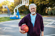 © Marko Geber - Portrait of a senior man holding basketball on outdoor court