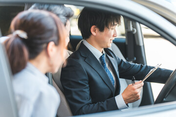 Wall Mural - 自動車購入・査定・買取にきた顧客を接客するセールスマンの若いアジア人男性
