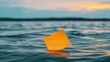 © Jss - A yellow sticky note floats on calm water during sunset, reflecting serene colors.
