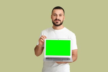 Wall Mural - young man holding laptop with blank screen on green background. mockup for design