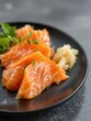 Fresh salmon sashimi with pickled ginger and greens on black plate