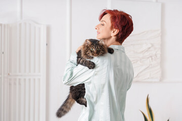 Wall Mural - Beautiful happy mature woman in pajamas with cute cat at home