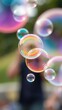 © Pawina - A close-up shot of colorful soap bubbles being blown against a blurred outdoor background, blowing, close-up, entertainment