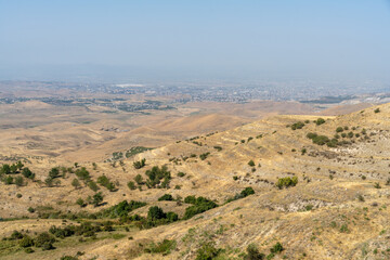 Wall Mural - A desert landscape with a city in the distance. The sky is clear and the sun is shining