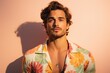 © MediaRaw - A man with a necklace and a floral shirt is standing in front of a pink wall