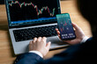 © sirichai - Investors analyze the data stock market index via smartphone screen to trade the stock chart for planning investments take profit, trade stock exchange market and cryptocurrency data, financial.