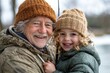 © ChaoticMind - A joyful elderly man with a woolen hat embraces a smiling child outdoors, both wearing cozy outfits, embodying warmth and connection during the winter season.