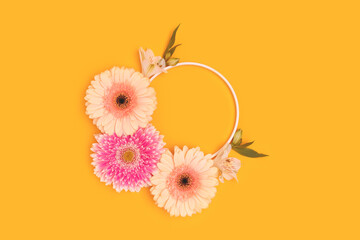 Wall Mural - round frame made of green leaves, alstroemeria and gerbera flowers on a yellow background.