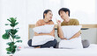 © Bangkok Click Studio - Portrait of young lovely sweet attractive asian happy couple love posing to camera smiling hugging pillow sitting on white bed in bedroom at home good time romantic together Valentine's day concept.