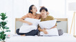 © Bangkok Click Studio - Portrait of young lovely sweet attractive asian happy couple love posing to camera smiling hugging pillow sitting on white bed in bedroom at home good time romantic together Valentine's day concept.