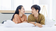 © Bangkok Click Studio - Portrait of young asian lovely sweet attractive cheerful happy couple love smile playing and relax on white bed in bedroom at home good time romantic together Valentine's Day and relationship concept.
