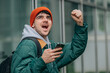 © carballo - student with backpack and mobile phone celebrating excited