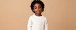 © Sanych - Young african american boy wearing white sweater and brown pants standing confidently against a simple beige background